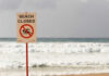 Sign indicating the beach is closed with a no swimming symbol