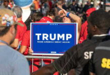 People holding Trump 2024 sign at a rally.