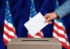 Hand casting a vote into a ballot box.