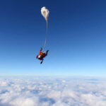 Skydiver descending through clouds with a parachute