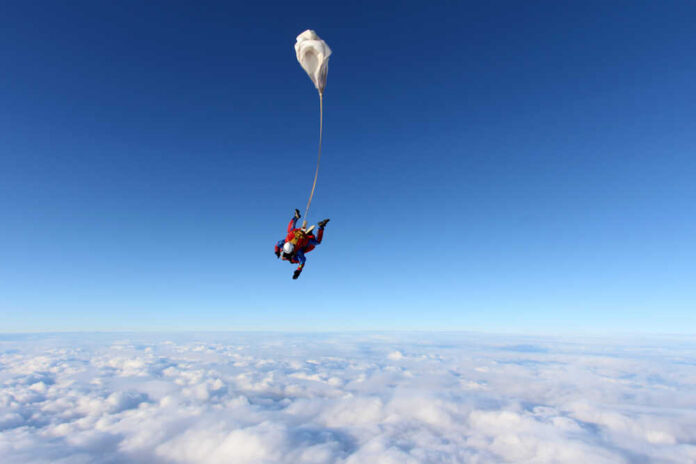 Tandem,Jump.,Skydivers,Are,Above,Clouds. Skydiver descending through clouds with a parachute