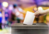 Hand placing ballot in voting box.