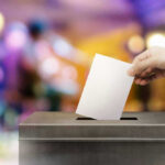 Hand placing ballot in voting box.