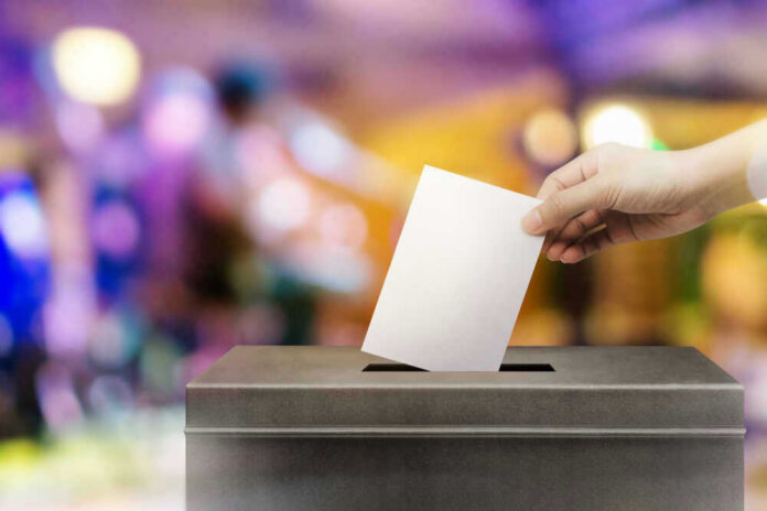 Hand placing ballot in voting box.