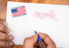Hands addressing an official election mail envelope
