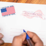 Hands addressing an official election mail envelope