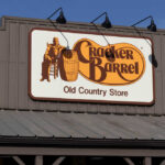 Sign for Cracker Barrel Old Country Store featuring a man sitting on a barrel