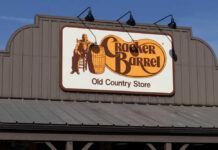 Sign for Cracker Barrel Old Country Store featuring a man sitting on a barrel
