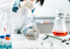 Scientist in a lab using a pipette to transfer liquid into a flask