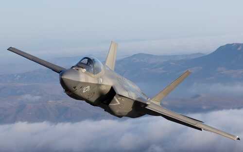 Very,Close,Side,View,Of,A,F-35c,Lightning,Ii,Over F-35 fighter jet flying above clouds with mountains in the background
