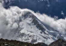 Snow-covered mountain peak partially obscured by clouds