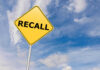 Yellow sign with RECALL text against blue sky.