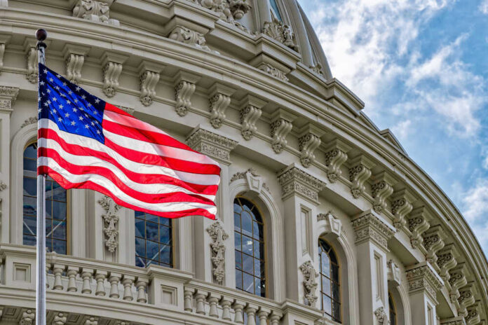 shutterstock_634024823 American flag in front of ornate building facade.
