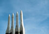 Four white missile launchers pointing upward against a blue sky