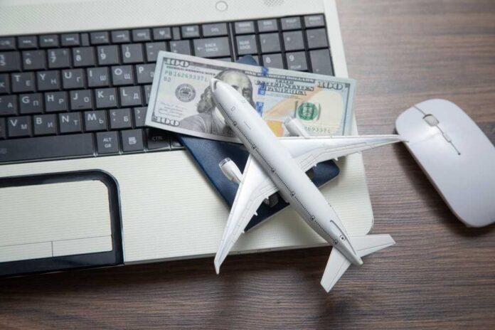 Toy,Airplane,With,A,Laptop,Computer. A model airplane on a laptop keyboard with a passport and cash