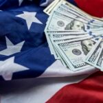 Stack of hundred dollar bills on an American flag