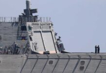 naval ship deck with two crew members standing near the stern