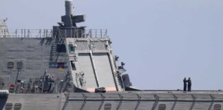 naval ship deck with two crew members standing near the stern