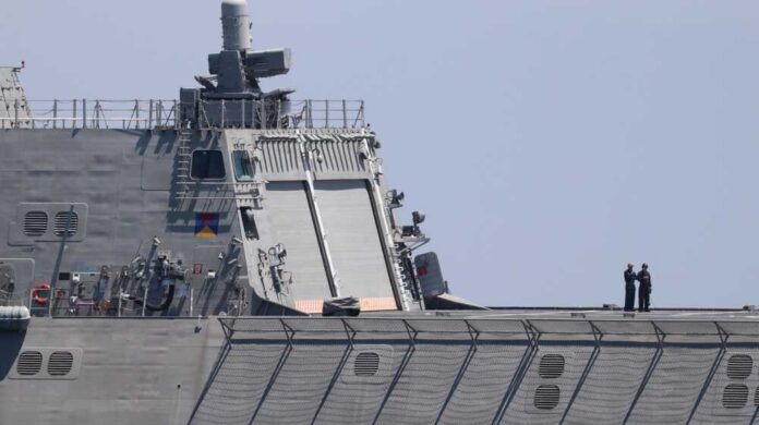 naval ship deck with two crew members standing near the stern