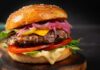 Close-up of a gourmet cheeseburger with lettuce, tomato, and pickled onions