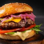 Close-up of a gourmet cheeseburger with lettuce, tomato, and pickled onions