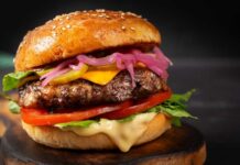 Close-up of a gourmet cheeseburger with lettuce, tomato, and pickled onions
