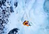 A climber ascending a frozen ice wall in a snowy landscape