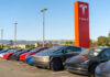 Tesla cars parked outside dealership with sign nearby