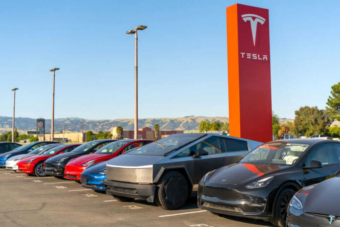 Tesla cars parked outside dealership with sign nearby