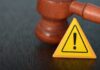 Judge's gavel beside yellow warning triangle sign