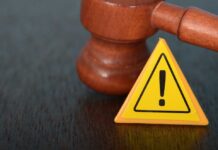 Judge's gavel beside yellow warning triangle sign