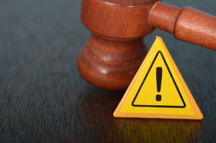 Justice,In,Action:,The,Gavel,And,Warning,Sign,Symbols,Of Judge's gavel beside yellow warning triangle sign