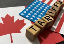 Wooden blocks spelling 'TARIFFS' on flags of Canada and the USA