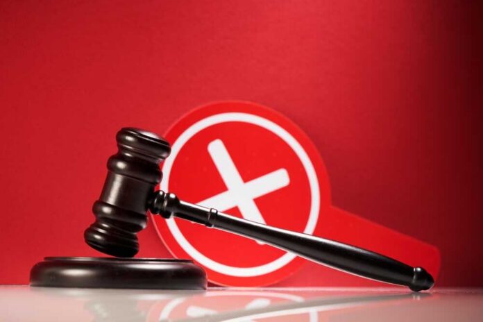 Wooden,Gavel,And,Cross,Mark,On,Red,Background. Judge's gavel with a red cross symbol in the background