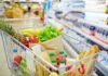 A shopping cart filled with fresh fruits, vegetables, and groceries