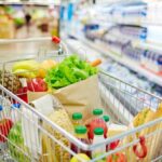 A shopping cart filled with fresh fruits, vegetables, and groceries