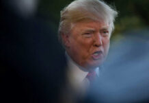 Donald Trump speaking outdoors, partially obscured.