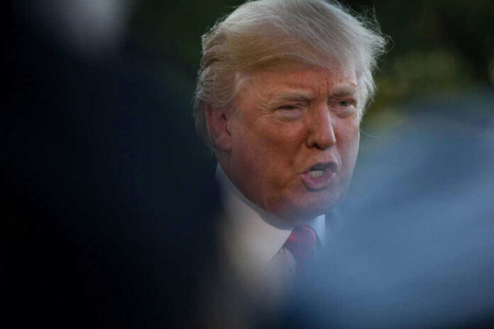 shutterstock_747962200 Donald Trump speaking outdoors, partially obscured.