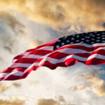 American flag waving against a cloudy sky.