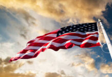 American flag waving against a cloudy sky.