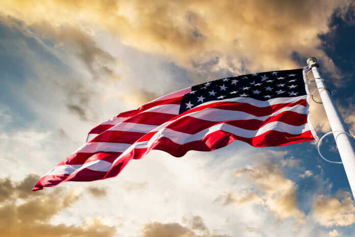 American flag waving against a cloudy sky.