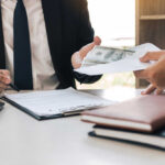 Two individuals engaged in a business transaction involving money and documents
