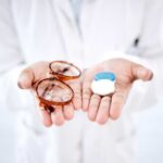 A person holding glasses and a contact lens case in their hands