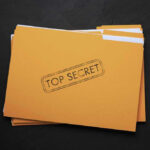 Yellow folder labeled Top Secret on black background.