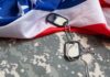 Military dog tags on camouflage fabric with an American flag