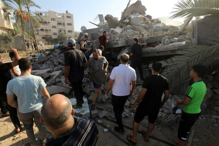 People examining rubble of collapsed building in sunlight.