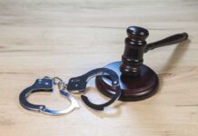 Gavel and handcuffs on wooden table