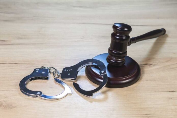 Judge,Hammer,For,Adjudication,With,Wooden,Stand,And,Handcuff.,Auction Gavel and handcuffs on wooden table