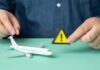 A person holding a warning sign next to a model airplane