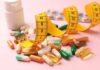 Assorted pills and a measuring tape on a pink background